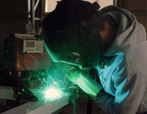 Homme réalisant des travaux de soudure pour fabrication d'enseigne - fabricant d'enseignes et de signalétiques